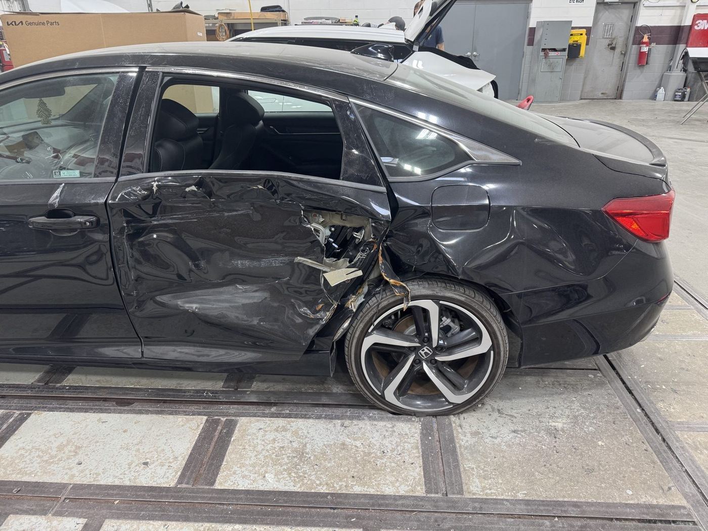 Honda Accord with severe driver-side collision damage to the rear door, quarter panel, and wheel area before repair at Bob Rohrman Collision Repair Center in Lafayette, Indiana